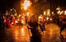 Photo of person standing holding a firey torch 