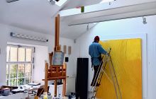 Artist in his studio working on a painting.